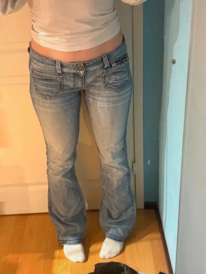 Vintage jeans från Only - Säljer ett par ljusblå bootcut jeans från Only då de tyvärr blivit för stora! De har låg midja och slitna detaljer. Jeansen har klassiska fem fickor, vita sömmar och en röd only-logga bak. Perfekta för en avslappnad och trendig look! (Inte mina bilder utan från hon jag köpte de av så de inte passar mig)