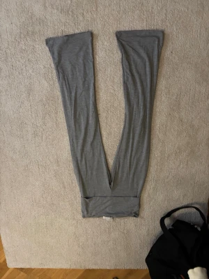 Grå mjuka leggings - Säljer ett par grå leggings i mjukt och stretchigt material. De har en enkel och stilren design med smal passform och bred resår i midjan. Perfekta för en avslappnad look eller till träning. Passar dig som gillar basic och bekvämt.