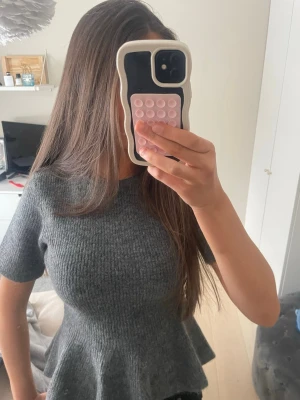 Grå stickad topp med volang - Grå stickad topp med kort ärm och volang nertill från hm.