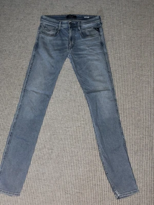 Replay Jeans - Säljer ett par ljusblå skinny jeans från Replay med klassisk femficksdesign och dragkedjegylf. Jeansen har smal passform och är tillverkade i stretchigt denimtyg för extra komfort. W32 L34