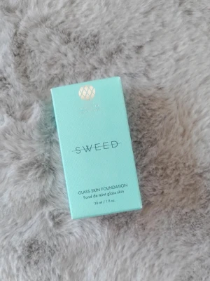 Sweed Glass Skin Foundation 01 - Glass Skin Foundation från Sweed i nyansen 01. Kommer i en stilren, ljusblå förpackning med guldiga detaljer. Innehåller 30 ml och ger en naturlig, glasliknande finish till huden. Perfekt för dig som vill ha en fräsch och jämn bas.
