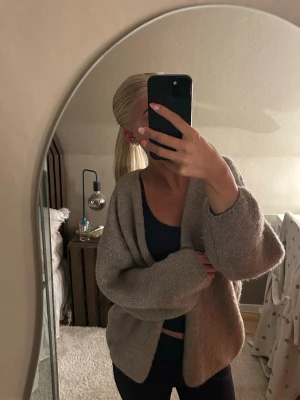 Brun oversized stickad kofta - Mysig brun stickad kofta med avslappnad, oversized passform och breda ärmar. Koftan har öppen front utan knappar och är perfekt att slänga över en topp