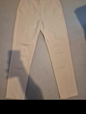 Beiga kostymbyxor  - Snygga beiga kostymbyxor från Gina Tricot i rak modell. Byxorna har hög midja, sidofickor. Perfekta att styla med en skjorta eller crop top för en clean look.