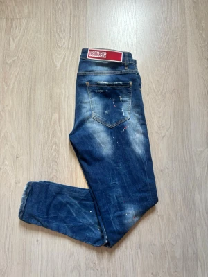 Blåa Dsquared2 jeans med slitningar - Tja, säljer ett par blåa jenas från Dsquared2 med schyssta slitningar och nice fade. Storlek 46. Jeansen har inga som helst defekter. Tveka inte på att slänga iväg ett prisförslag eller på att fråga något som du undrar! Mvh Valentino