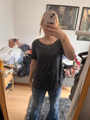 Svart t-shirt med pärldetaljer - Säljer en svart t-shirt med korta ärmar och snygga pärldetaljer runt halsen. 