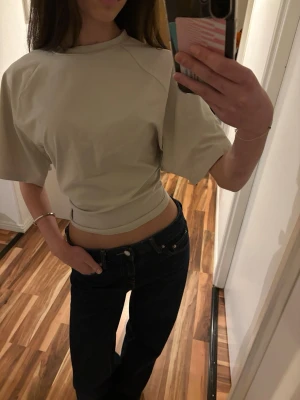 Beige croppad topp från Adidas - Säljer denna supersnygga tröjan från Adidas i storlek M. Tight i midjan men lös uppe vid ärmarna. Aldrig använd men saknar prislapp.