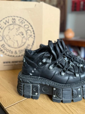 Svarta platåboots från New Rock - Tuffa svarta platåboots från New Rock med kraftig sula och industriella detaljer. Skorna har snörning, metallnitar och coola mönster på både ovandel och sula. Perfekta för dig som gillar alternativ stil och vill sticka ut.