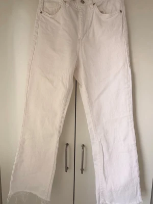 Vita ankle jeans från Zara - Säljer ett par vita ankle jeans från Zara i storlek 36. Jeansen har hög midja och fransiga benslut. 