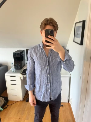 Blå linneskjorta från Massimo Dutti - Säljer en snygg blå skjorta från Massimo Dutti i 100% linne. Skjortan har klassisk krage, knappar framtill och långa ärmar. Det följer även med 2 extra knappar, hör gärna av dig vid frågor!
