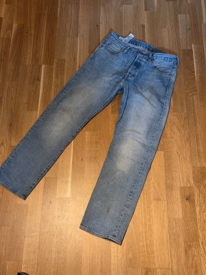 Ljusblå raka jeans från Levi's - Säljer ett par klassiska 501 ljusblå jeans från Levi's med rak passform. Jeansen har en tidlös tvätt och är tillverkade i slitstark denim. Perfekta för en avslappnad och trendig look. Tveka inte på att skriva om ni har nån fråga om jeansen!