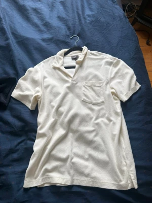 Två piké-liknande toppar i frotté - Säljer två piké-liknande toppar i mjuk frotté, en i vit och en i grå. Båda har kort ärm, öppen krage och bröstficka. Perfekta för en avslappnad och trendig look.