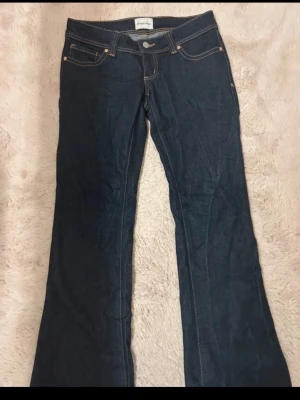 Mörkblå bootcut jeans från abrand jeans  - Snygga mörkblå bootcut jeans från abrand jeans med klassiska fem fickor och kontrastsömmar. Jeansen har en något utsvängd passform nedtill och är tillverkade i kraftigt denimtyg. Perfekta för en avslappnad och trendig look. Lite slitna ned till 
