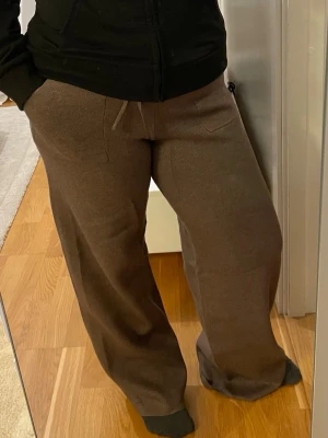 Bruna vida mjukisbyxor med dragsko - Mjukisbyxor med breda ben och dragsko i midjan. Byxorna har två stora fickor framtill. Ganska lång för mig som är 158cm och mycket stretchig. Skulle rekommendera till XL i storlek. Använd några gånger.                                                      Leverans med Instabox eller mötesplats.