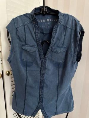 Blå ärmlös topp från Karen Miller st. M - Snygg blå ärmlös  topp  från Karen Miller med två bröstfickor och knappar framtill. Toppen har en markerad söm och en lätt figurnära passform. Perfekt för en avslappnad och cool stil.