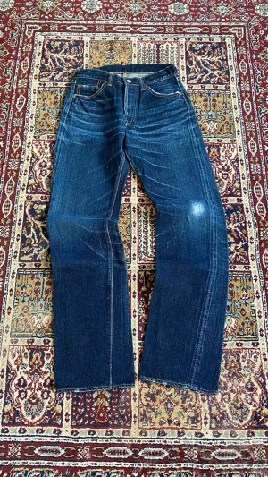 Samurai bootcut blå jeans vintage - Säljer ett par klassiska blå samurai jeans  och slitningar för en vintage look. Jeansen har fem fickor, kontrastsömmar och läderpatch bak i midjan. Materialet är kraftig denim i bomull. Perfekta för dig som gillar tidlös och avslappnad stil.