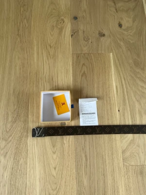 Hm bälte brun - Snyggt brunt bälte från hm  med klassiskt monogrammönster och silverfärgat hm-spänne. Perfekt accessoar för att lyfta din outfit med en lyxig touch. Kommer med originalask och certifikat.