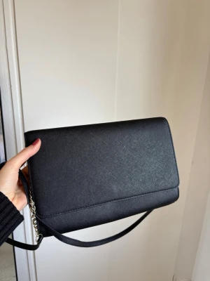 Svart stilren axelväska - Snygg svart axelväska i slätt konstläder med enkel och stilren design. Från HM