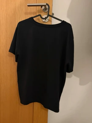 Svart basic t-shirt - En enkel svart t-shirt med rund hals och korta ärmar. Perfekt till jeans eller shorts för en clean och avslappnad look. Tillverkad i mjukt material som känns skönt mot huden.