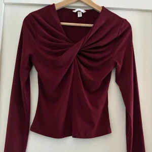 V-ringad topp - Säljer en figurnära, långärmad topp i mjuk, stretchig trikå. Köpt förra sommaren men aldrig använd, bara tvättad. Orig. pris 249kr Säljer också samme topp men i grått färg. Se annan annons.  Från rökfritt hem men vi har hundar.