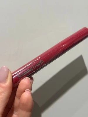 Makeup Mekka Stunning Length Mascara - Snygg mascara från Makeup Mekka i modellen Stunning Length. Hylsan är vinröd och har en smal, avlång form. Texten på förpackningen är i silver och mascaran är vattenresistent. Perfekt för dig som vill ha långa och definierade fransar.