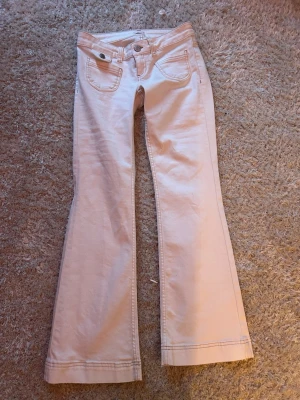 Vita bootcut jeans med fickor - Nypris 699kr. Jeansen är aldrig använda pga för liten storlek. Säljer ett par vita bootcut jeans med klassiska fem fickor och snygga sömdetaljer. Jeansen har utsvängda ben och låg midja.