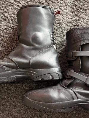 Svarta motorcykelstövlar från IXS stl 43 - Säljer ett par halvhöga svarta motorcykelstövlar från IXS med robust sula och två spännen framtill. Tillverkade i slitstarkt läder och utrustade med vattentätt membran (Quilt-Tex). Perfekta för dig som vill ha både skydd och stil på hojen.