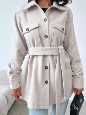 Beige overshirt med knytskärp - Stilren beige overshirt med knappar framtill, två bröstfickor och ett matchande knytskärp i midjan. Overshirten har klassisk krage och långa ärmar, perfekt att bära över en t-shirt eller topp för en trendig lager-på-lager-look.