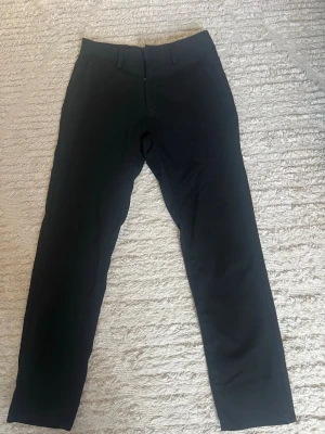 Svarta raka kostymbyxor från Zara - Snygga svarta kostymbyxor med rak passform och klassisk midja. Byxorna har bälteshällor, diskreta fickor fram och bak samt stängs med dragkedja och hake. Perfekta för en stilren look och passar till många olika outfits. Storlek 36. Passar om du är runt 170.