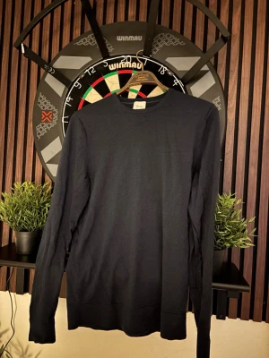 Mörkblå stickad tröja Calvin Klein - Snygg mörkblå stickad tröja från Calvin Klein i maskintvättbar ull. Tröjan har rund halsringning, långa ärmar och ribbade muddar vid ärmslut och nederkant. Perfekt för dig som gillar stilrena och klassiska plagg.