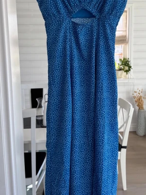 Bik Bok Blå långklänning i stl S - Snygg blå långklänning med små vita blommor och ett litet urklipp framtill. Klänningen har ärmlös design och en avslappnad passform. 