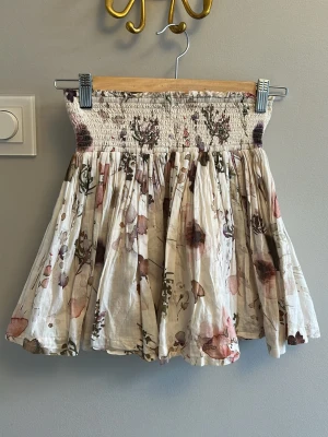 Blommig volangkjol - Supersöt kjol med volanger från pomp de lux. Kjolen är krämvit med blommigt mönster 