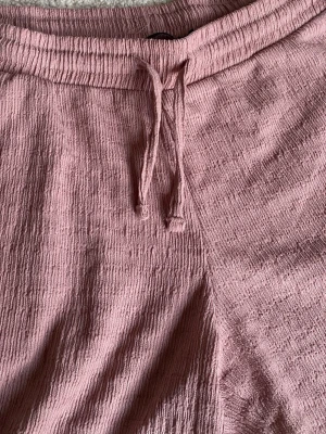 Ljusrosa shorts med snörning från 157 - Ljusrosa shorts från 157 med resår och snörning i midjan. Tillverkade i ett mjukt,   Perfekta för varma dagar och enkla att styla med olika toppar.