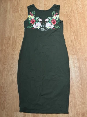 Grön blommig långklänning - Mörkgrön långklänning med ärmlös design och färgglada blommor upptill. I super bra skick!💕