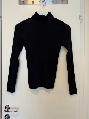 Svart ribbstickad polotröja - Snygg svart ribbstickad polotröja med lång ärm och tight passform. Jag minns inte märke men antingen vero Moda eller Ginatricot, plaggen ligger i flyttlåda så därav inga fler bilder.