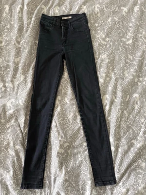 Svarta skinny jeans från Levis - Säljer ett par svarta skinny jeans från Levis. Jeansen har hög midja, klassisk femficksdesign och smala ben. Materialet är stretchigt för en bekväm passform. Perfekta till en cool vardagslook.