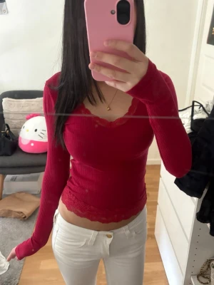Röd ribbad topp med spetsdetaljer - Snygg röd långärmad topp med ribbad struktur och spetsdetaljer vid halsringning och nederkant. Från hollister. 💕skriv om du har frågor, kolla min profil för annat fint!!