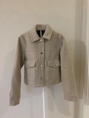 Beige kappa - Säljer en beige kroppad kappa från Zara i storlek XS. Kappan är aldrig använd och har inga defekter.