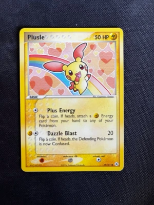 Plusle Pokémonkort EX Deoxys 2004 - Säljer ett original Plusle Pokémonkort från EX Deoxys-serien, utgivet 2004 av Pokémon/Nintendo. Kortet har gul ram, färgglad illustration med hjärtan och regnbåge, samt text på engelska. Perfekt för samlare eller Pokémonfans!
