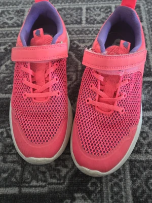 Neon Rosa sneakers i 36 - Säljer snygga neonrosa sneakers med meshdetaljer och kardborreband i storlek 36. Skorna har elastiska skosnören och en vit sula. Insidan är lila för en cool kontrast. Kan användas som gympaskor säljer de då de är för små. De är lite skitiga vid sulan men kommer tvättas vid köp💕
