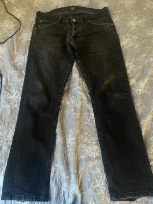 Svarta raka jeans från Lee - Snygga svarta jeans från Lee med rak passform och klassisk femficksdesign. Jeansen har metallknapp med Lee-logga och är tillverkade i denim. Perfekta för en avslappnad och stilren look.