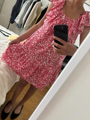 Rödvit blommig volangklänning - Supersöt kort klänning med rödvitt mönster och volangdetaljer!❤️Klänningen har en lös passform o, perfekt till sommarn+skolavslutning . 