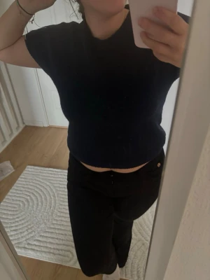 Mörkblå croppad stickad topp - En mörkblå croppad stickad topp med korta ärmar och rund hals. Perfekt för en avslappnad och trendig stil. Enkel design som är lätt att matcha med olika outfits.
