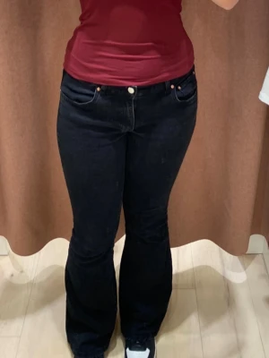 Svarta bootcut jeans - 📌STÅR STORLEK 40 MEN PASSAR ÄVEN 38/M📌Säljer ett par svarta bootcut jeans med klassisk femficksdesign och låg midja. Jeansen har en snygg utsvängd passform nertill och stängs med knapp och dragkedja. Perfekta för dig som gillar en tidlös och trendig look.