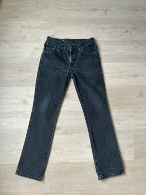 Svarta Nudie Slim Jim Jeans Storlek W32 L34 - Mycket fina Nudie Jeans i svart färg. Jeansen är i mycket bra skick och sparsamt använda. |  Äkta som allt annat jag säljer! ✅ |  Storlek: W32 L34| Skick: Mycket Bra Skick - en slitning men inget tydligt (SE SISTA BILD) | Färg: Svart | Märke: Nudie | Modell: Jeans |   Hör gärna av dig vid frågor så svarar jag så fort jag kan! 😁 |  (SKU - 138)