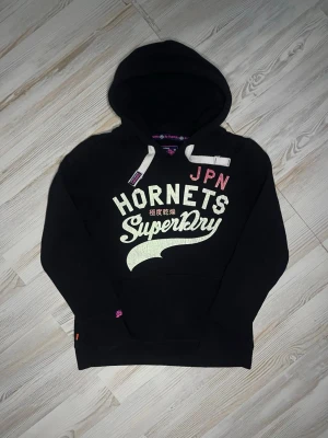 Svart superdry hoodie - Säljer denna svarta hoodie från superdry i ett befintligt skick🤩 längd:60cm bredd 48cm Storlek S men passar xs. hör gärna av dig er vid funderingar samt snabbaffärer🙌🏻