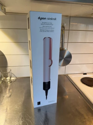 Dyson Airstrait hårstyler - Dyson Airstrait är en innovativ hårstyler i vit och roséguld design. Den använder luft för att räta ut håret utan extrem värme. Perfekt för dig som vill styla håret skonsamt och effektivt. Snygg och modern design med sladdanslutning.
