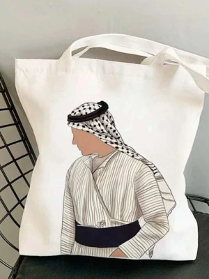 Vit shoppingväska med illustration ( Palestina keffya) - Trendig vit shoppingväska i bomull med en snygg illustration av en person i traditionell klädsel på framsidan. Väskan har långa handtag och är perfekt att bära över axeln. Enkel och stilren design som passar till många tillfällen.