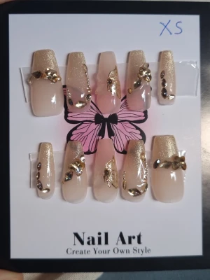 Nude lösnaglar med guldglitter Strl XS - 10st långa lösnaglar tillverkad av matt akryl, som är stark och hållbar. Nagelfil och applikator inkluderas.                                          Mått( båda vänster och höger är samma )  Tumme =       1,8 cm bredd längd 2,5 cm Pekfinger =   1,5 cm bredd längd 2 cm Långfinger = 1,5 cm bredd längd 2cm Ringfinger = 1,5 cm bredd längd 2 cm Lillfinger =    1,2 cm bredd  längd  2 cm      OBS! Storleken är baserad på manuell mätning och kan variera med 1–2 cm. 