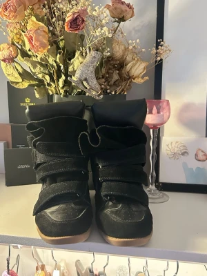 Svarta Isabel marant klackar - Isabelmarant klackar i st 36. Skorna har en mix av mocka och textil, samt en ljus brun gummisula. De har högt skaft och en modern, edgy look som sticker ut. Använt fåtal gånger så toppen skick 