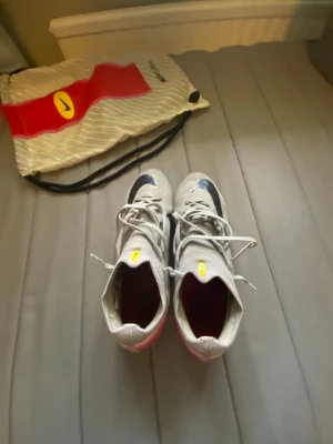 Nike Mercurial Vapor 16 Elite FG - Snygga Nike Mercurial fotbollsskor i silver med svarta detaljer och rödrosa sula. Skorna har snörning och en aerodynamisk form för maximal fart på planen. Tillverkade i syntetmaterial och levereras med en Nike-påse. Perfekta för dig som vill sticka ut på matchen.